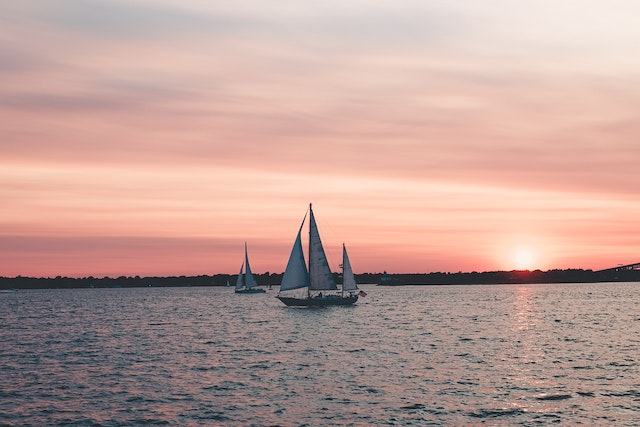 white sailboats in the water at sunset